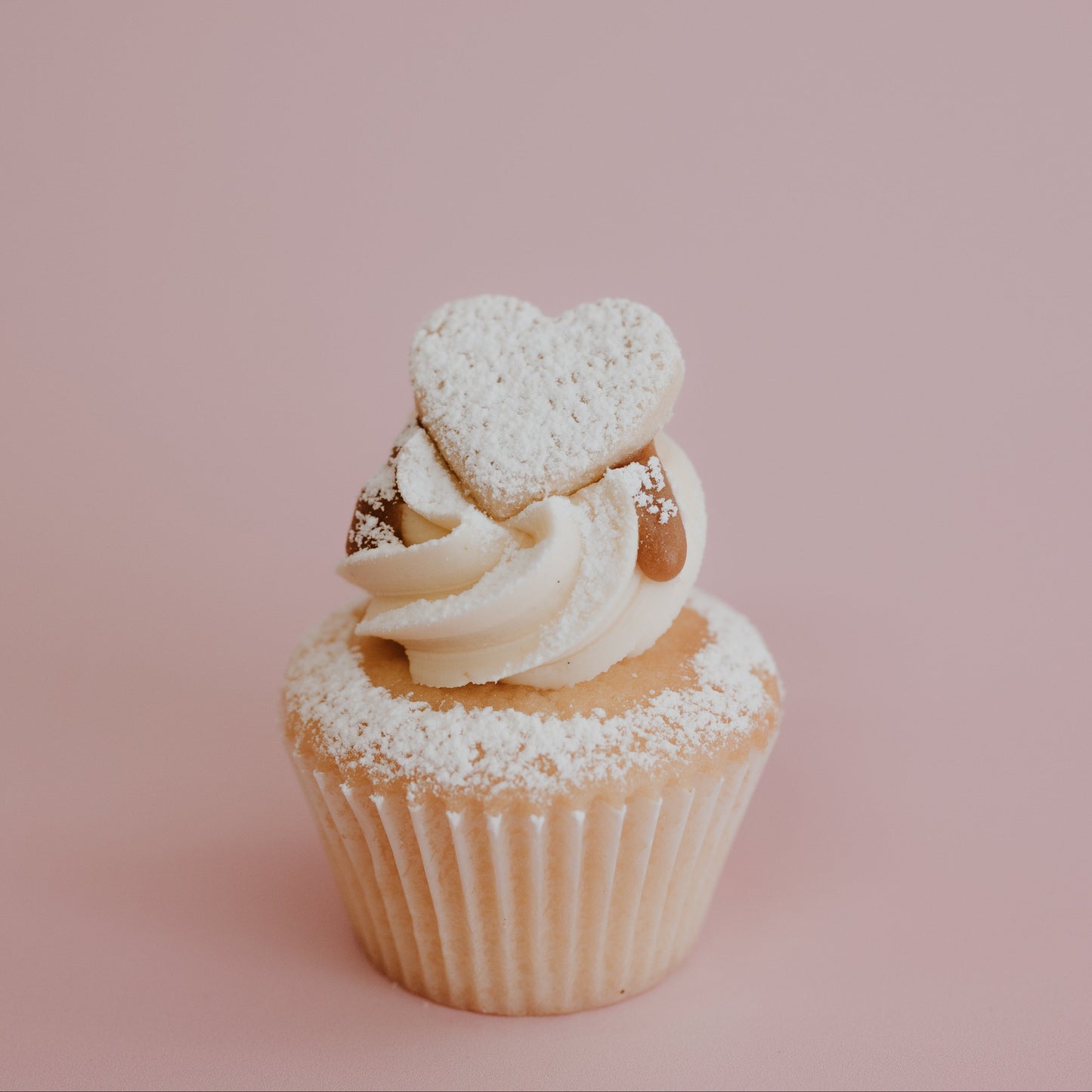 Cupcake with heart-shaped decoration on a pink background
