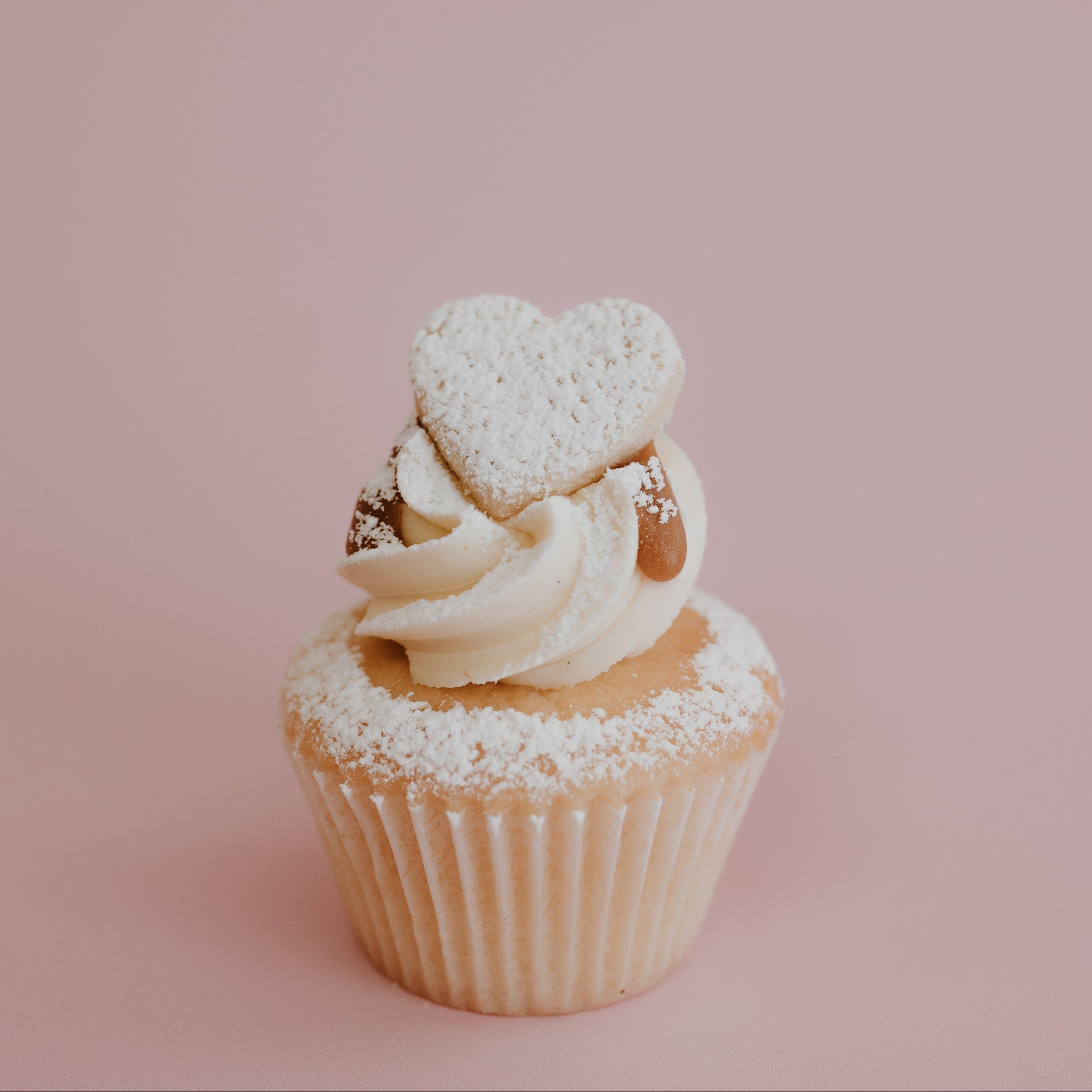 Cupcake with heart-shaped decoration on a pink background