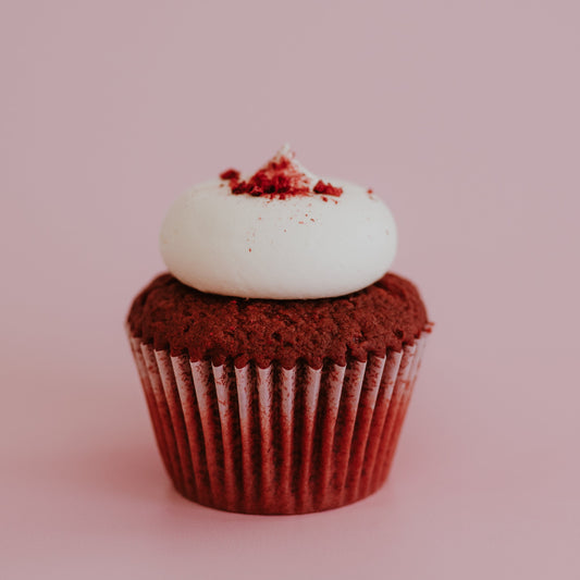 Red velvet cupcake with white frosting on a pink background